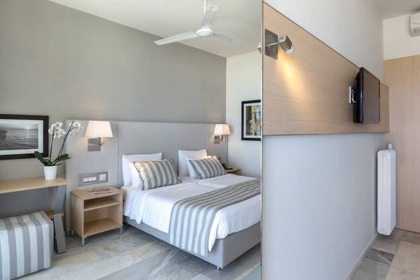 Schlafzimmer im Acharavi Beach Hotel mit Bett, Nachttischen und Klimaanlage.
