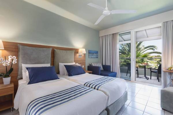 Doppelbettzimmer im Acharavi Beach Hotel mit Blick auf eine Terrasse und einen Garten.