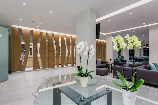 Lobbybereich des Acharavi Beach Hotels mit weißen Orchideen auf einem Glastisch.