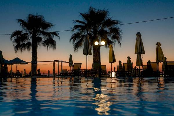 Pool am Abend im Acharavi Beach Hotel mit Palmen und Sonnenschirmen.