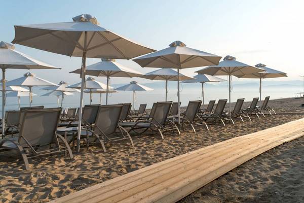 Reihe von Liegestühlen und Sonnenschirmen am Strand des Acharavi Beach Hotels