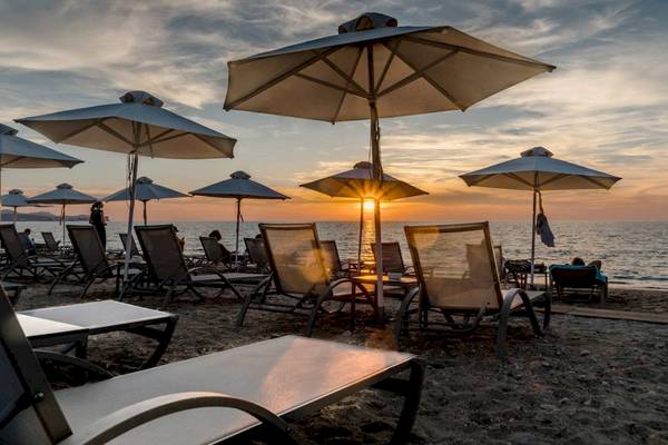 Strand des Acharavi Beach Hotels mit Sonnenschirmen und Sonnenuntergang