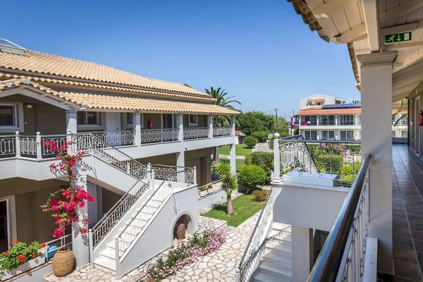 Außenansicht des Acharavi Beach Hotels mit gepflegtem Garten und Balkonen.