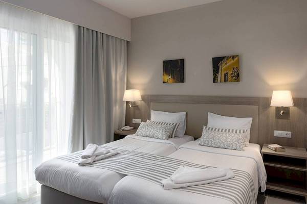 Doppelzimmer im Acharavi Beach Hotel mit zwei Betten, weißem Bettwäsche und Dekor.