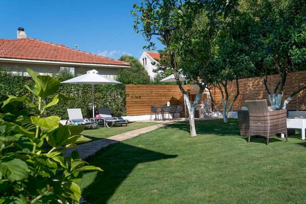 Außenbereich des Acharavi Beach Hotel mit Garten, Liegestühlen und Tischen