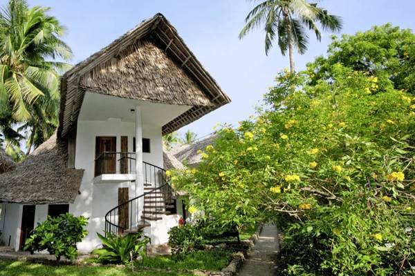 Außenansicht des Severin Sea Lodge tropischen Hauses mit Strohdach, umgeben von Pflanzen und Bäumen.