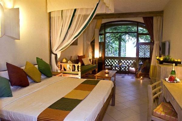 Schlafzimmer in der Severin Sea Lodge mit großem Bett, weichen Kissen und einem Ausblick auf die Außenterrasse.