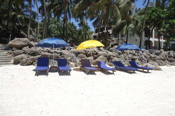 Strand der Severin Sea Lodge mit Liegen und Sonnenhüten vor einem Gebäude