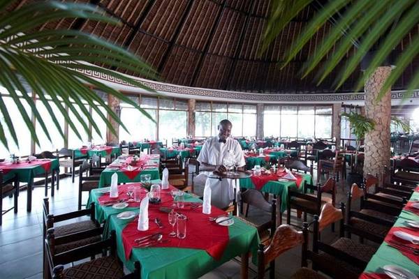 Innenansicht des Restaurants der Severin Sea Lodge mit gedeckten Tischen und einem Kellner.