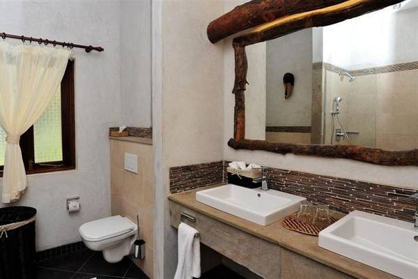 Badezimmer der Severin Sea Lodge mit zwei Waschbecken, Spiegel und Toilette.
