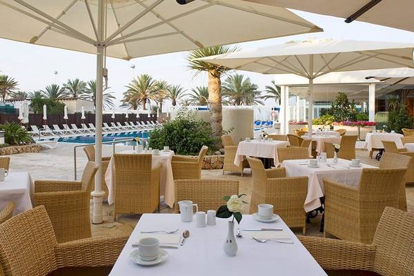 Außenbereich des Restaurants im HM Gran Fiesta Hotel mit Tischen, Stühlen und Sonnenschirmen.