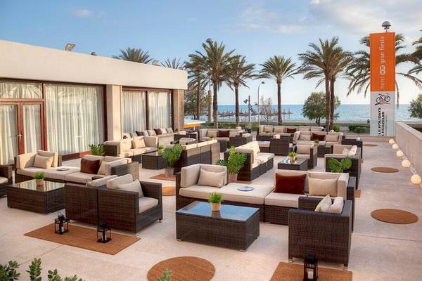 Loungebereich des HM Gran Fiesta Hotels mit Blick auf den Ozean und Palmen.