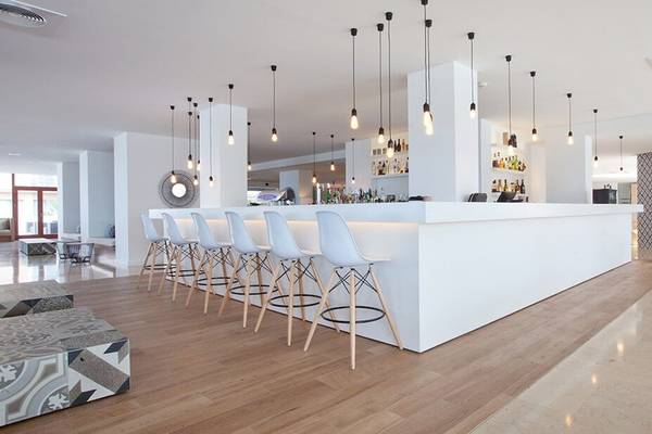 Innenbereich der Bar im HM Gran Fiesta Hotel mit weißen Stühlen und Theke.
