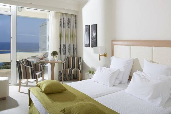 Doppelzimmer im Electra Palace Rhodes mit Meerblick, inklusive Balkon, Tisch, Stühlen und Bett mit weißen Kissen.