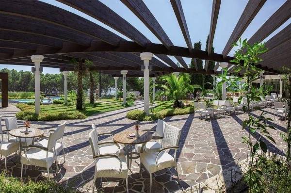 Außenbereich des Niko Hotels mit Pergola, Tischen und Stühlen im Freien.