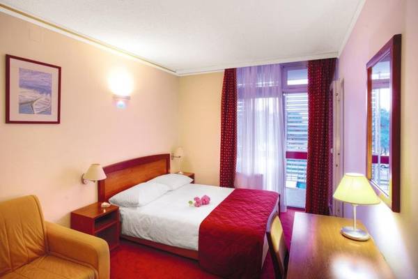 Innenansicht eines Hotelzimmers im Niko Hotel mit Bett, Lampe und Dekor.