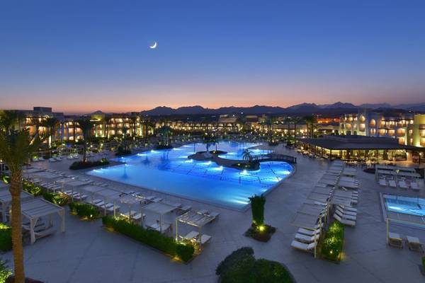 Abendlicher Außenbereich des Steigenberger Alcazar mit großen Swimmingpool und vielen Sonnenliegen.