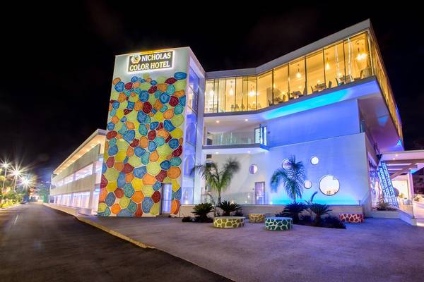 Außenansicht des Nicholas Color Hotel bei Nacht mit bunten Kreisen an der Wand und blauen Lichtern.
