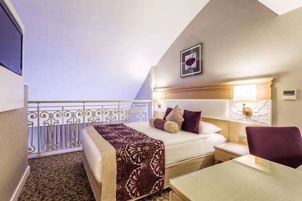 Innenansicht eines Hotelzimmers der Villa Side Residence mit Bett, Schreibtisch und Balkon.