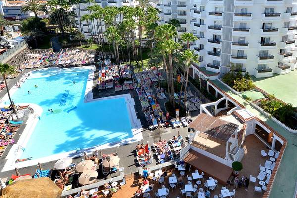 Luftaufnahme des Servatur Waikiki Hotels mit Swimmingpool, Sonnenliegen und Besuchern.