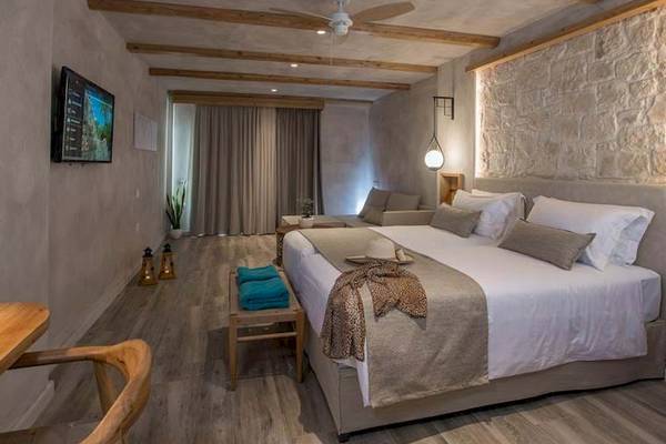 Innenansicht eines Zimmers im Cactus Mare Hotel mit Bett, Fernseher und Holzmöbeln.