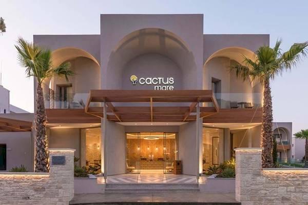 Vorderansicht des Cactus Mare Hotels mit zwei Palmen und einer verglasten Eingangstür.