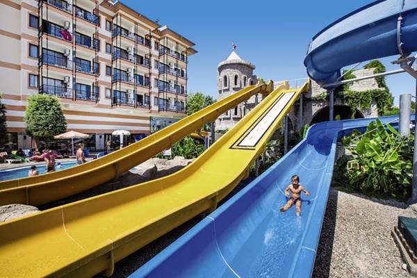 Ein junger boy rutscht auf einer blauen wasserrutsche im Freien am Adalya ArtSide Hotel.