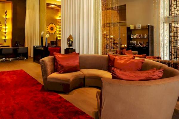 Lobby des Paradisus Playa del Carmen Hotels mit L-förmiger Couch, rotem Teppich und Dekor.