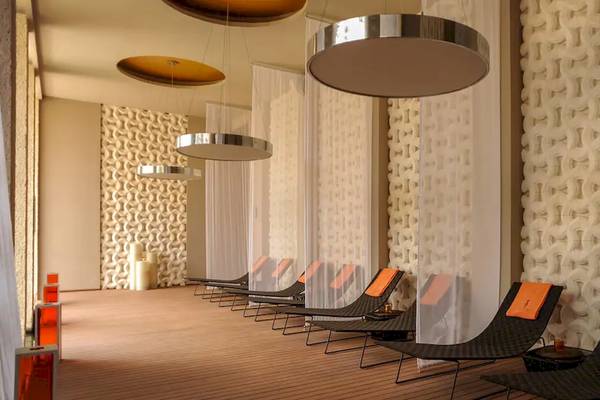 Spa-Lounge im Paradisus Playa del Carmen Hotel mit mehreren schwarzen Liegen und orangefarbenen Kissen.