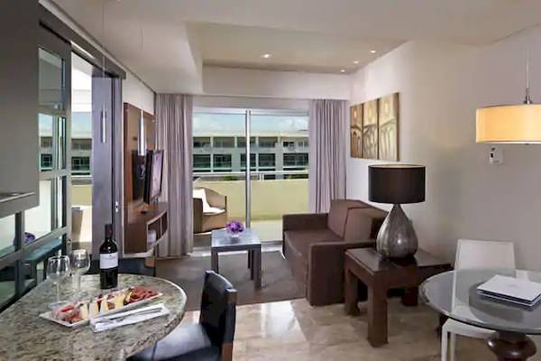 Innenansicht der Suite im Paradisus Playa del Carmen mit Wohnzimmer, Essbereich und Balkon.