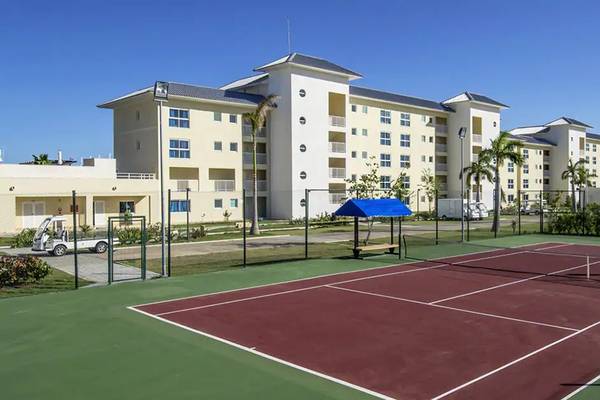 Tennisplatz vor dem Melia Marina Varadero Hotel mit einem blauen Sonnendach und einem leeren Tennisnetz.