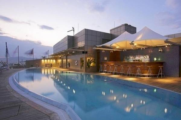 Dachterrasse des Melia Athens Hotels mit Swimmingpool, Bar und Tischen am Abend