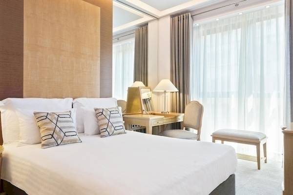 Innenansicht eines Schlafzimmers im Melia Athens Hotel mit Doppelbett, Schreibtisch und Fenstern.