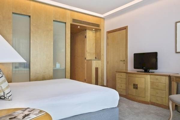 Innenansicht eines Schlafzimmers im Melia Athens Hotel mit Doppelbett, Fernseher, Lampen und Schreibtisch.