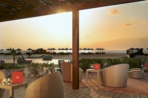 Aussicht auf die Lounge-Ecke am Strand des Melia Athens Hotels mit Sonnenuntergang.