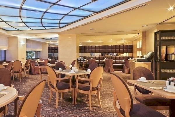 Frühstücksraum des Melia Athens Hotels mit vielen Tischen und Stühlen, Glasdecke und moderner Einrichtung.
