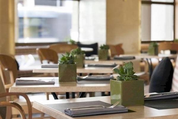 Innenansicht des Restaurants des Melia Athens Hotels mit Tischen, Stühlen und Pflanzen.