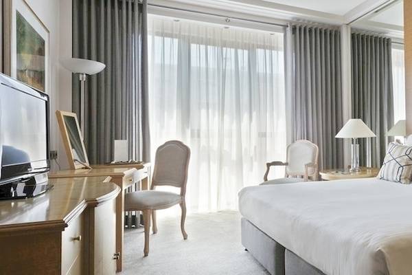 Schlafzimmer im Melia Athens Hotel mit großem Bett, Fernseher, Schreibtisch, Stühlen und Lampen.