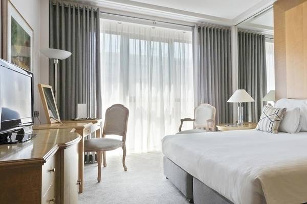 Schlafzimmer im Melia Athens Hotel mit großem Bett, Fernseher, Schreibtisch und Stühlen.