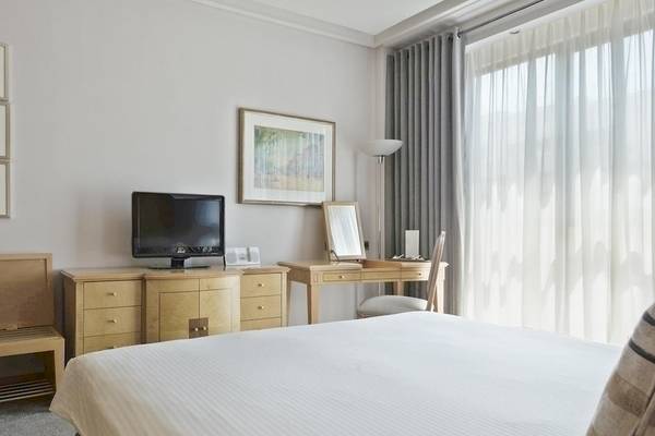 Innenansicht eines Hotelzimmers im Melia Athens mit Fernseher, Schreibtisch und Fenstern.
