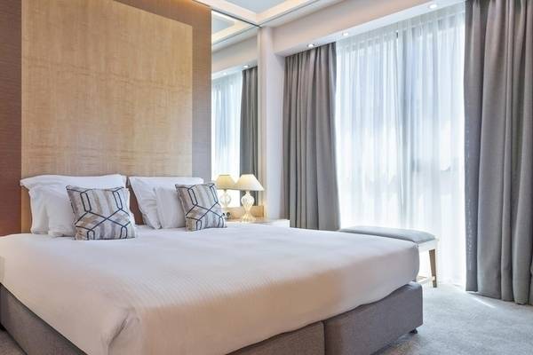 Hotelzimmer im Melia Athens mit einem großen Bett, Lampen und Dekorelementen.