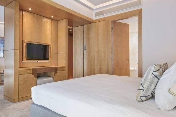 Schlafzimmer im Melia Athens Hotel mit Doppelbett, Fernseher und Holzmöbeln.