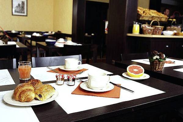 Frühstückstisch im Mercure Paris Montmartre Sacré-Coeur Hotel mit Croissants, Getränken und Früchten.