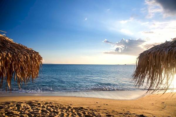 Strand mit Sonnenschirmen und Ozean im Hintergrund bei Sonnenuntergang
