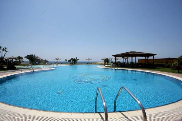 Großer Swimmingpool im Plaza Beach Hotel mit Sonnenschirmen und Blick auf das Meer.