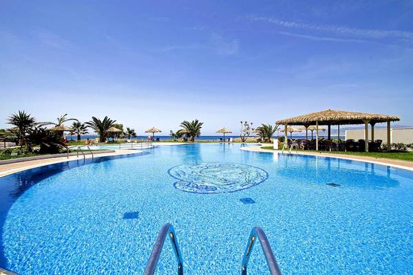 Pool im Plaza Beach Hotel mit Blick auf das Meer und Sonnenschirmen.