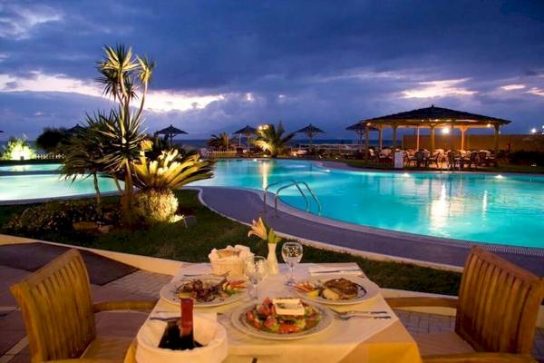 Essbereich am Pool des Plaza Beach Hotels bei Nacht mit Essen, Wein und einer Aussicht auf den Ozean