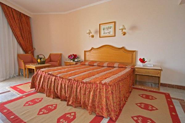 Hotelzimmer im Sea Star Beau Rivage mit zwei Betten, Nachttischen, Stühlen und Wanddekoration.