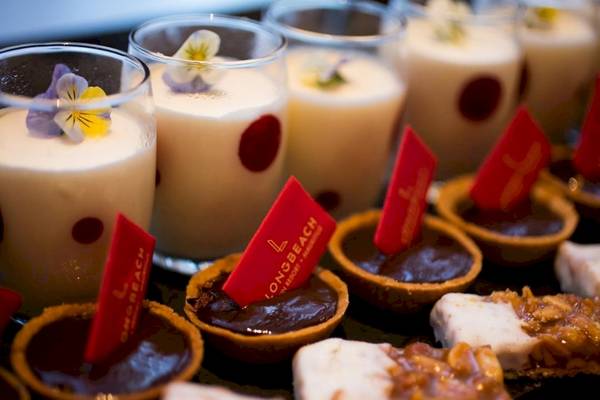 Desserts vom Long Beach Mauritius Resort, einschließlich Schokoladenkuchen und schaumiger Getränken mit Blüten.