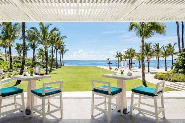 Terrasse im Long Beach Mauritius Hotel mit Meerblick und grüner Rasenfläche.